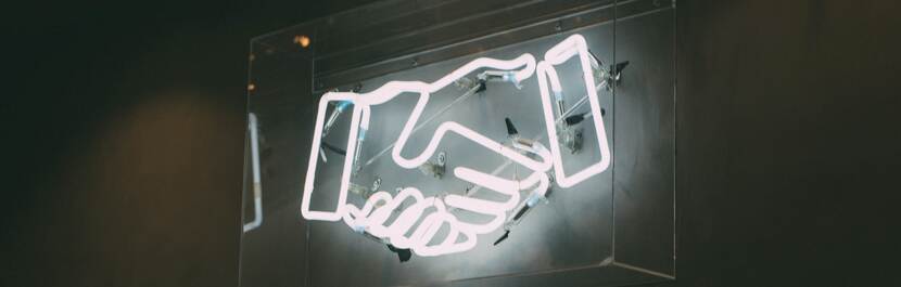 een foto van een neon bord met schuddende handen