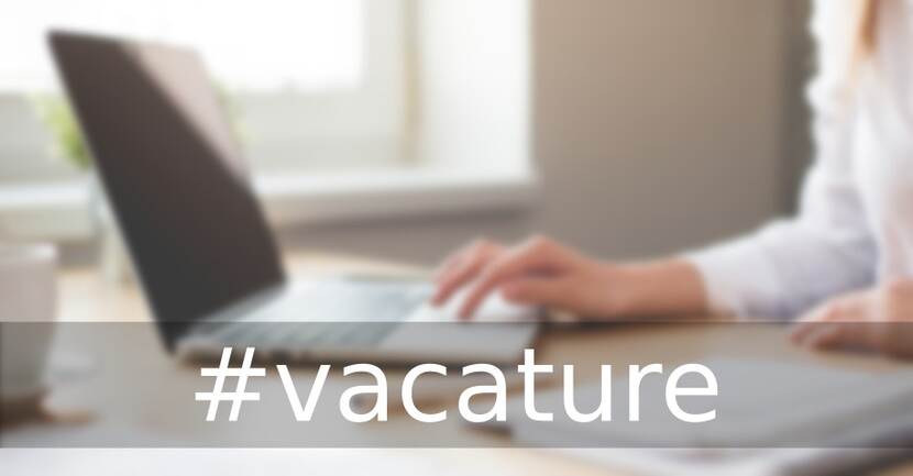 Vervaagd beeld van iemand achter de laptop met daaroverheen in grote letters hashtag Vacatures