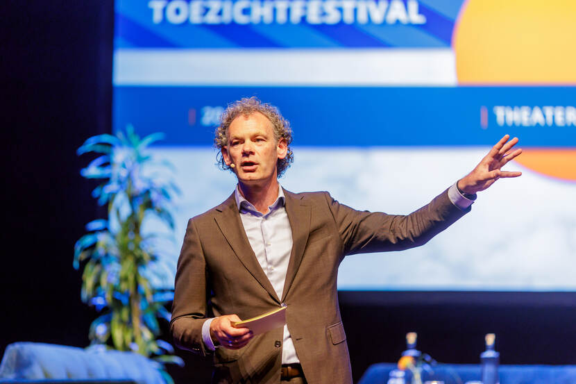 Dagvoorzitter Mark Bressers op podium