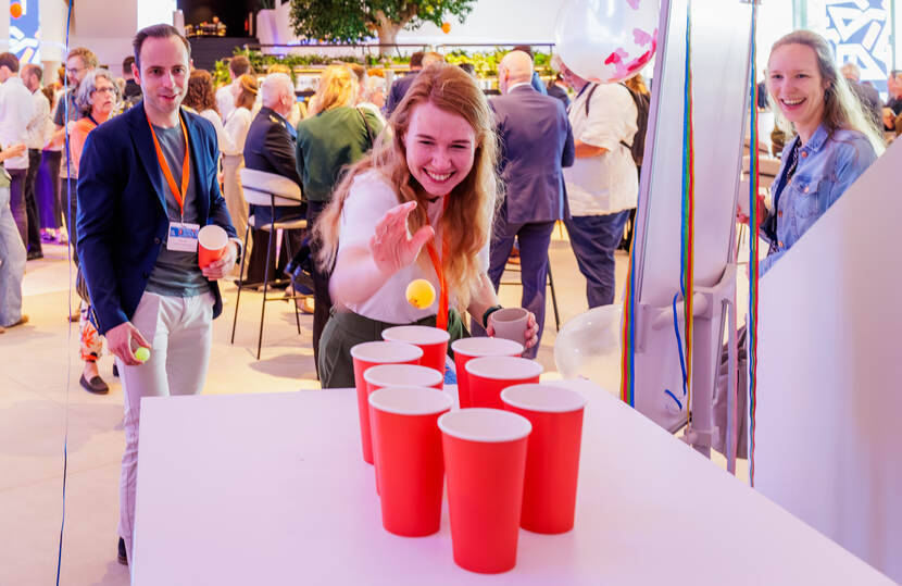 Jonge vrouw gooit in spel een balletje in ene drinkbeker