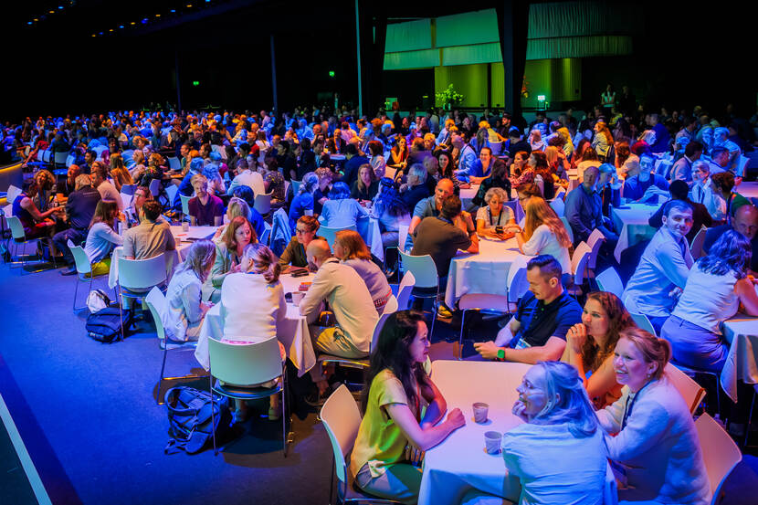 Blauw gekleurde zaal vol bezoekers