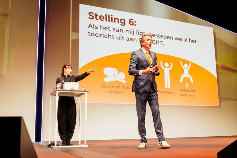 Man en vrouw op een podium voor een geprojecteerde stelling